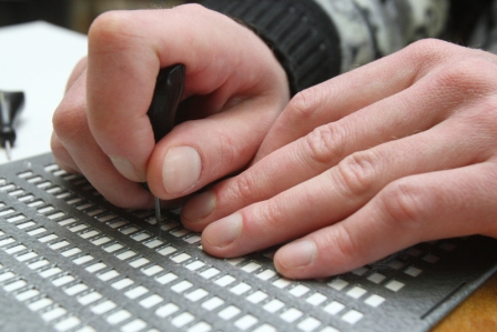 A hand typing on a Braille keyboard